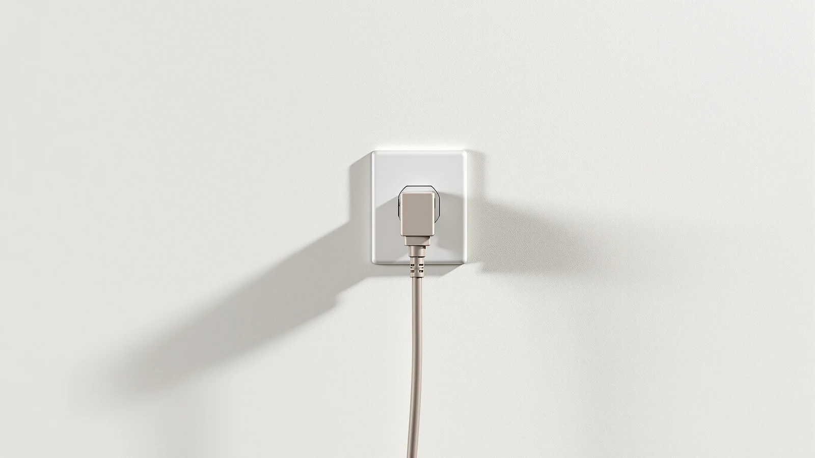 Close-up of a space heater's power cord plugged into a white wall outlet, the cable running down a plain wall